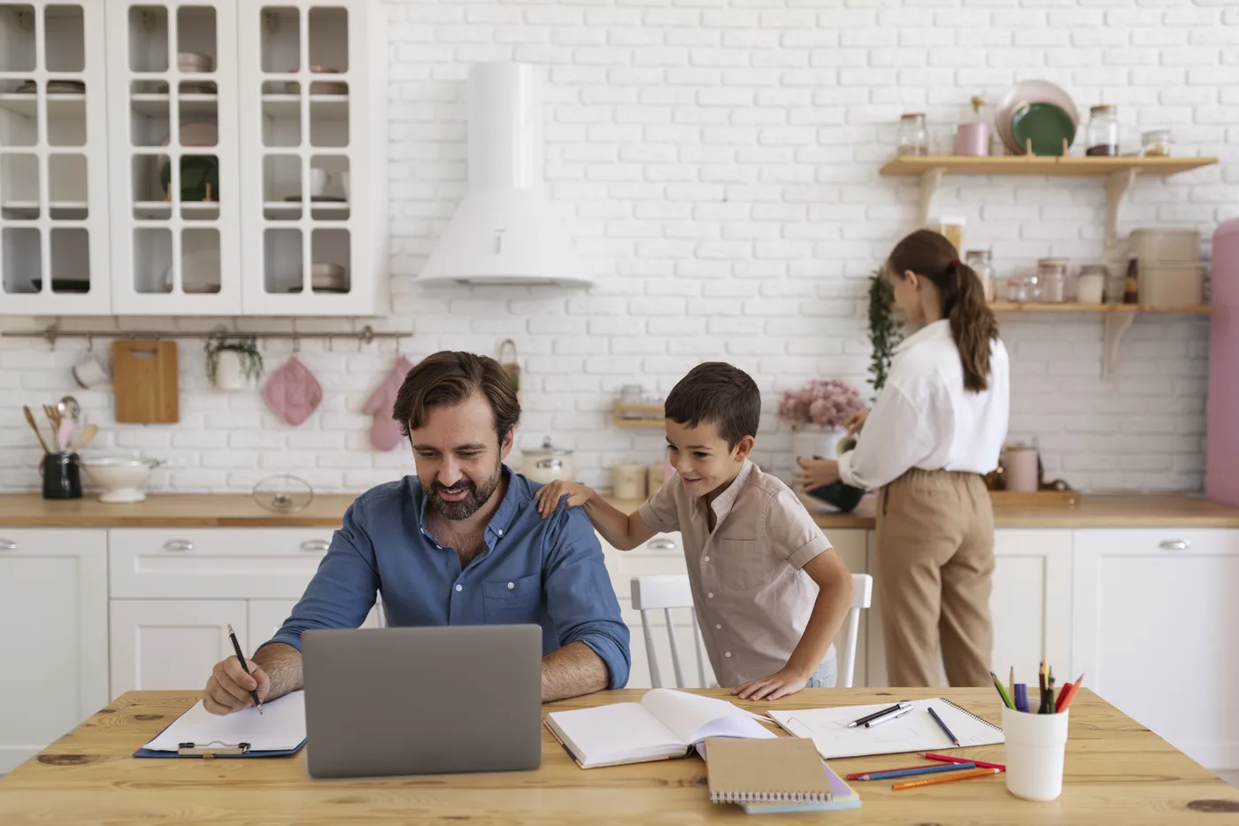 A family at a kitchen table reviewing paperwork together on a laptop