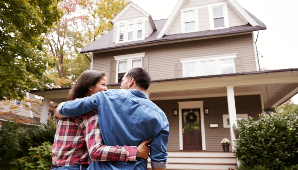 A couple standing outside their new house after a successful U.S. spouse visa journey